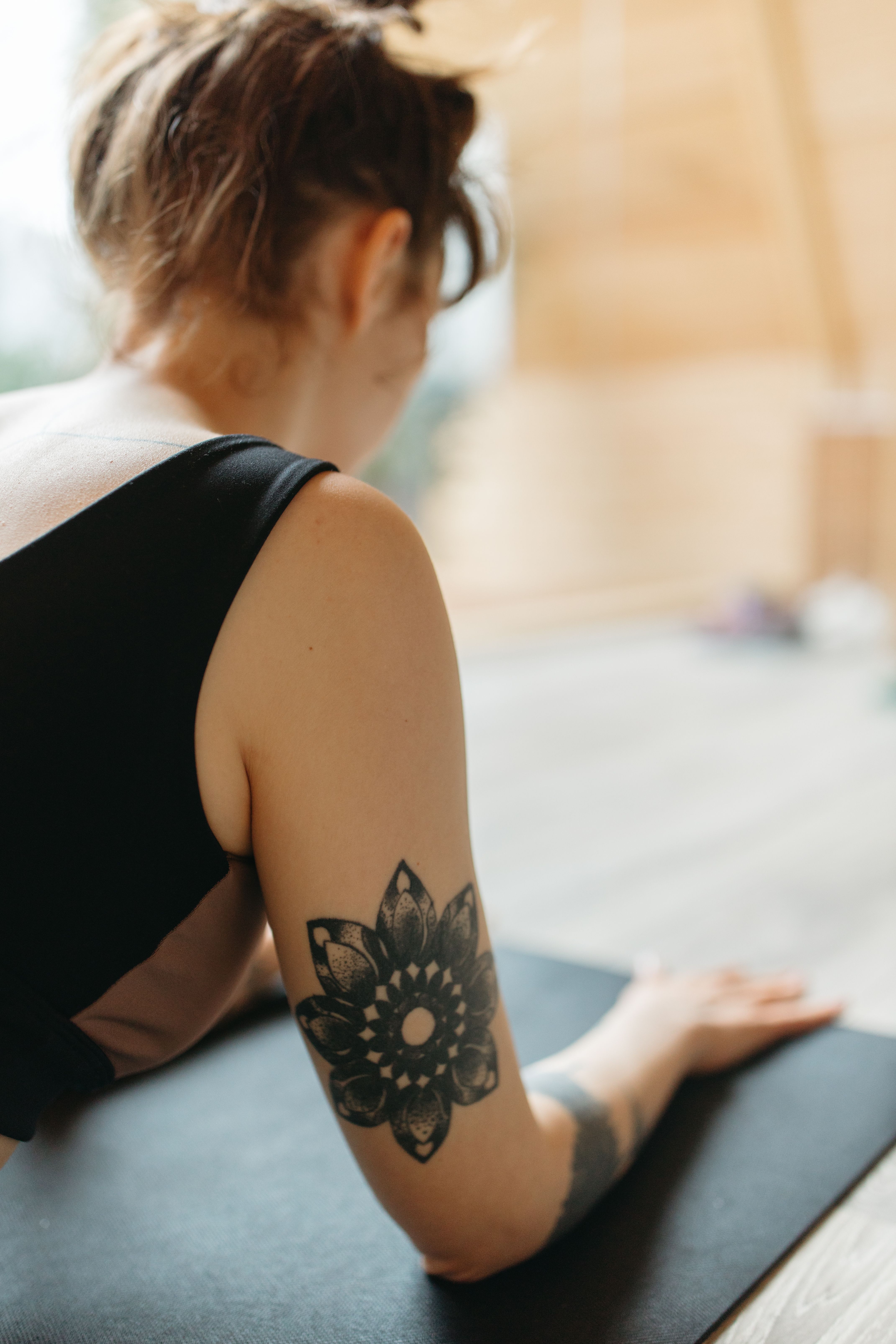 Mulher meditando com tatuagem de mandala dotwork nas costas